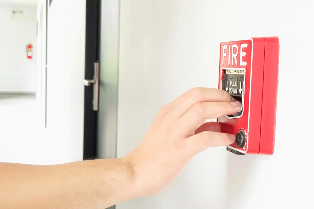A hand seen in the image setting off the fire alarm